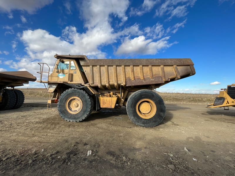 Large rigid dump truck on a dirt quarry site under a blue sky