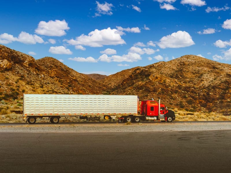 Red semi-trailer truck travelling on a desert highway