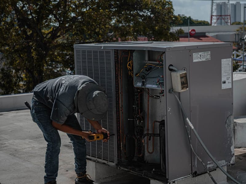 Technician servicing an outdoor air-conditioning unit on a rooftop