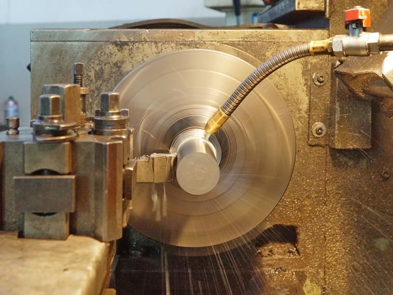 Metal lathe turning a steel workpiece with coolant spraying