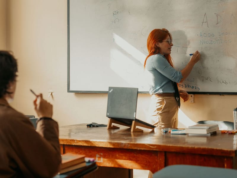 Teacher writing on a whiteboard in front of an adult class